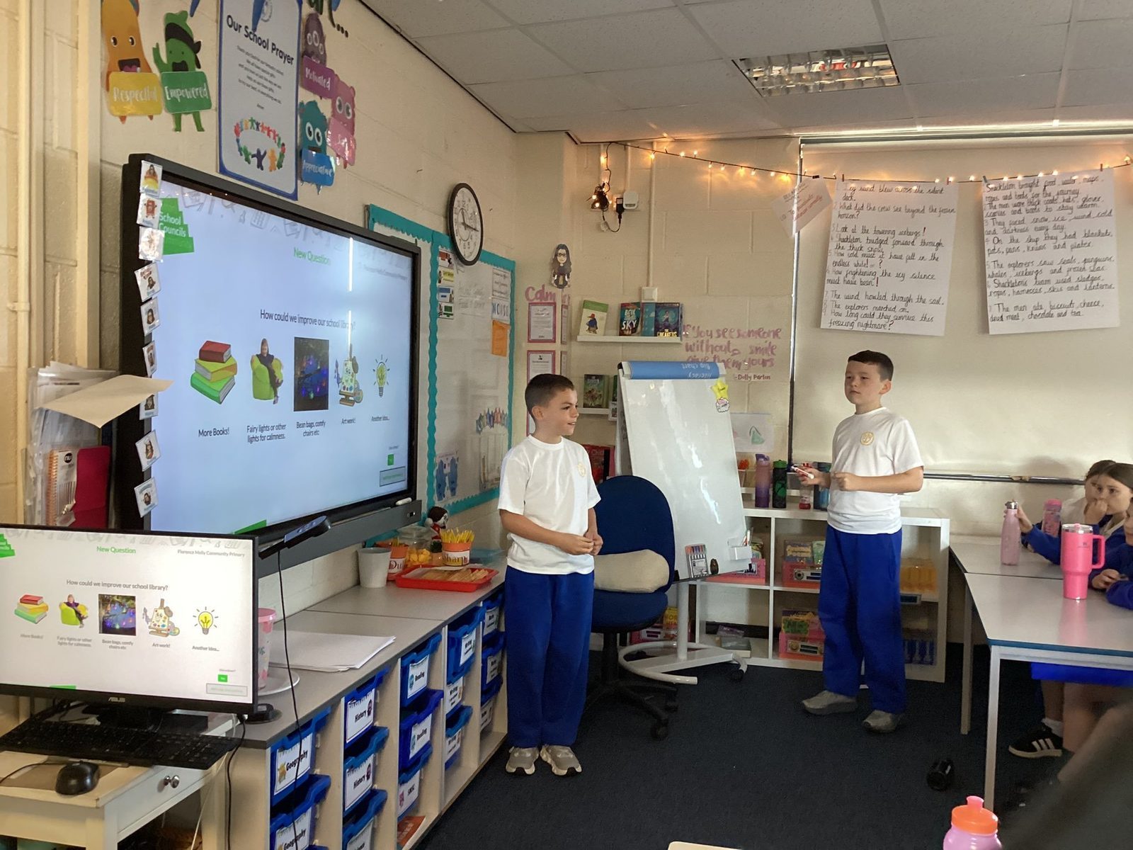 School council training in practice: two pupils at Florence Melly Community Primary lead a class meeting, with the question How could we improve our school library and five picture options on the board